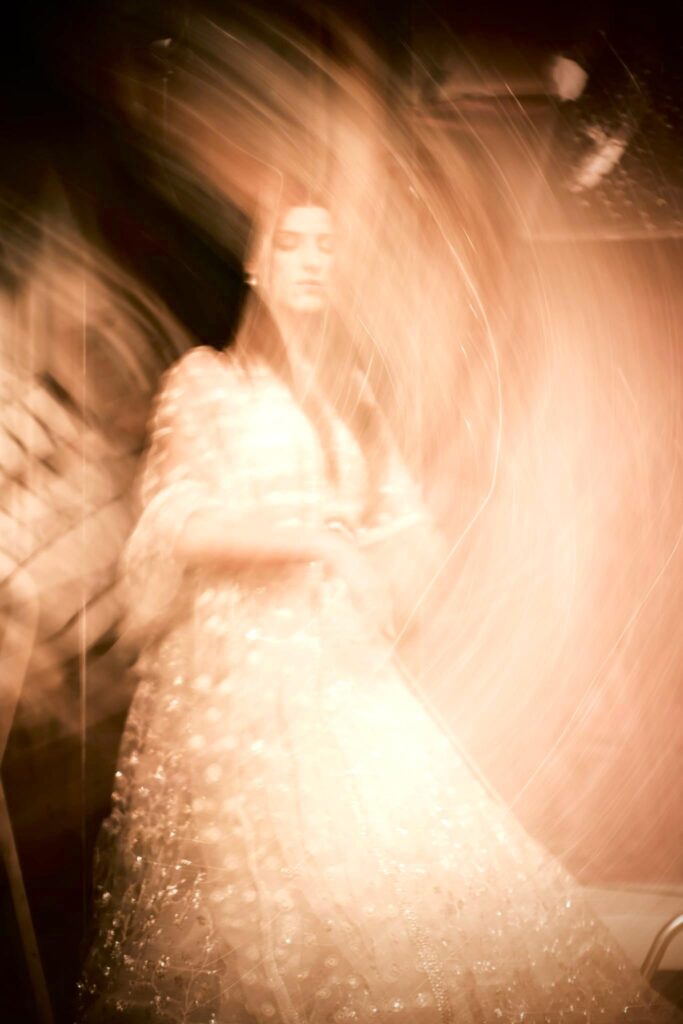 Accueil 5 Silhouette de Manal Cherki enveloppée dans un tourbillon de lumière chaude et dorée. Elle porte une élégante robe brodée, illustrant l'énergie humaine et la grâce en mouvement.